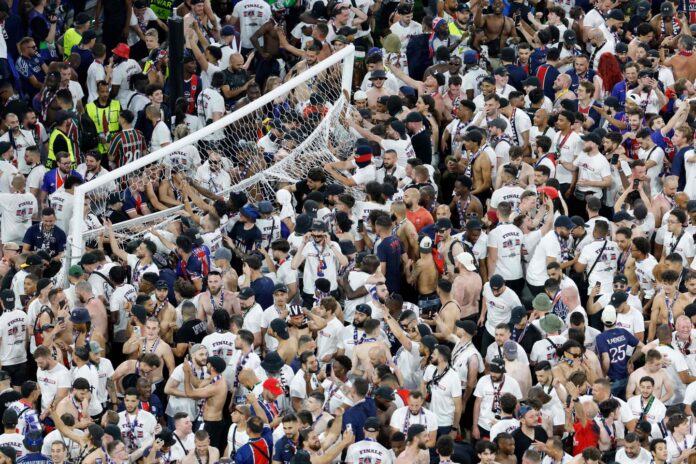 Police have to hold back PSG fans as they try to rush the field after Champions League win