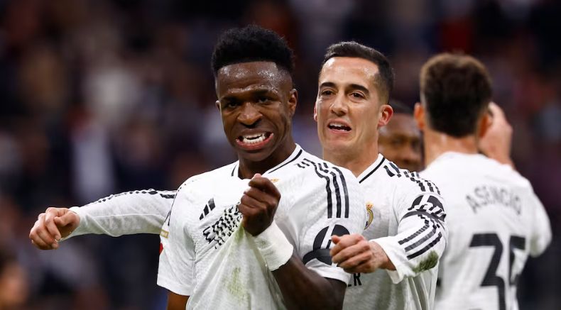 Vinicius celebrates by grabbing the Real Madrid badge.